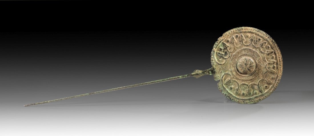 Große Scheibenkopfnadel.: Große Scheibenkopfnadel. Luristan, früheisenzeitlich, 1000 - 650 v. Chr. H 39cm, ø der Scheibe 11,7cm. Getriebene Bronze. Auf der Scheibe zentral eine Rosette, darum Fries aus Ranken und Knospen.