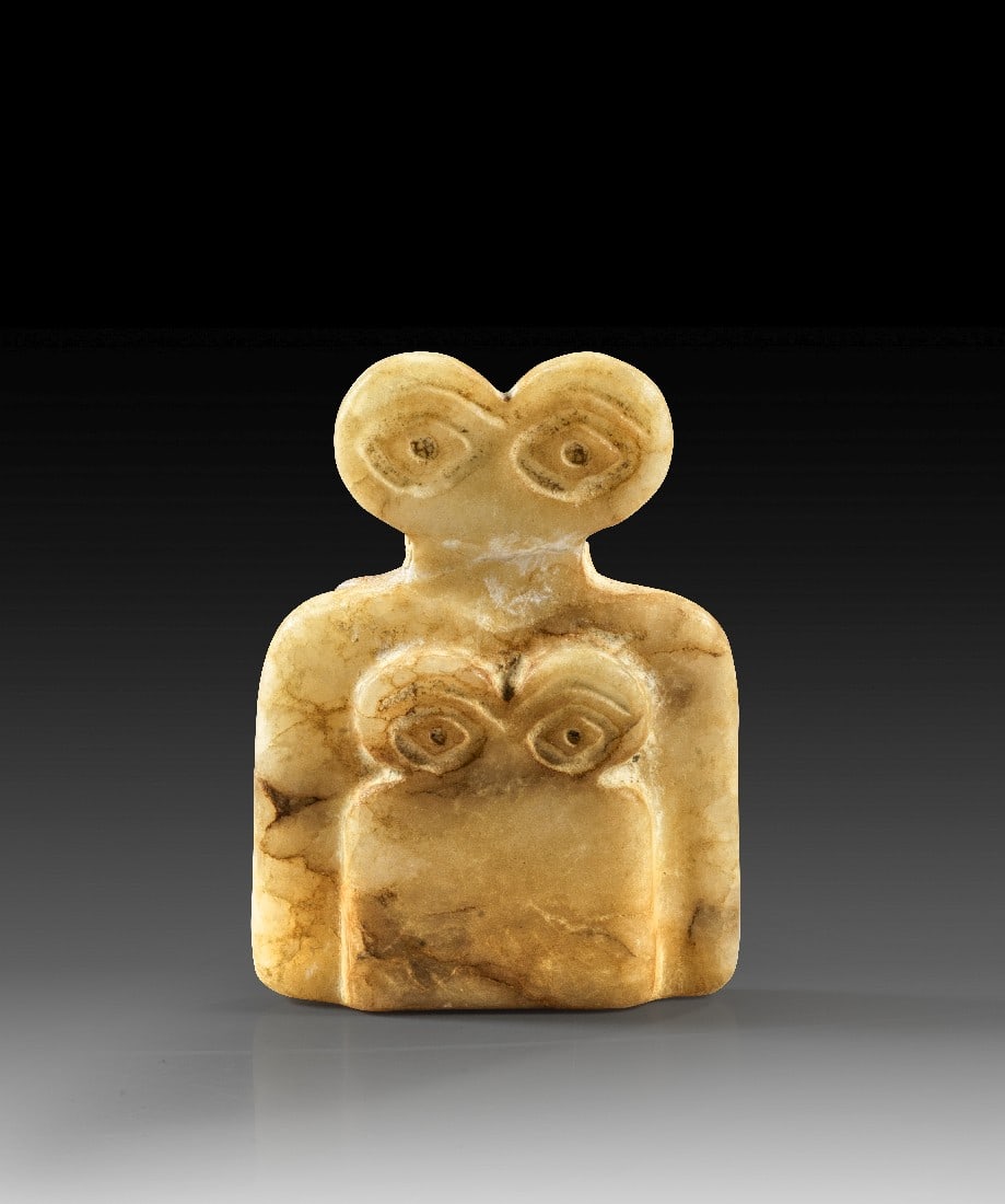Augenidol mit Kind vom Tell-Brak-Typus.: Augenidol mit "Kind" vom Tell-Brak-Typus. Mesopotamien, 2. Hälfte 4. Jt. v. Chr. H 5,4cm. Marmor. Ein größeres und ein kleineres Idol hintereinander gestaffelt mit eingeritzten Augen. Am Hals