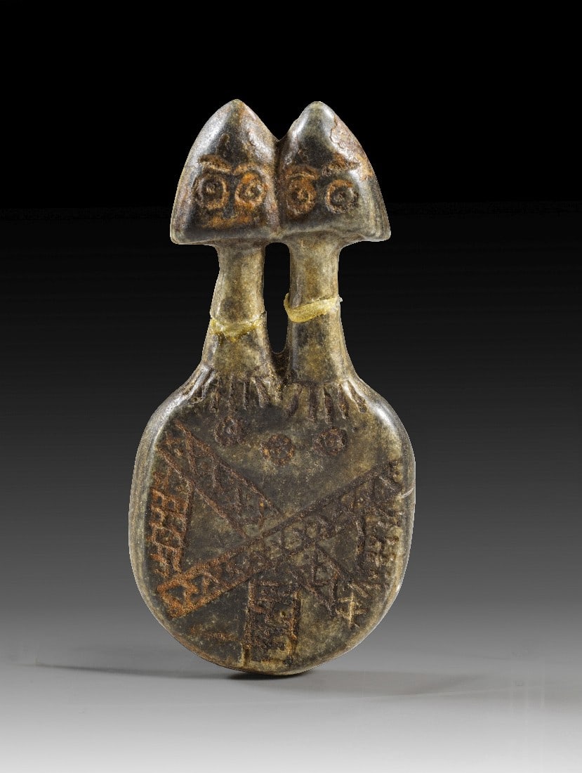 Doppelköpfiges Idol.: Doppelköpfiges Idol. Mesopotamien, 2. Hälfte 4. Jt. v. Chr. H 6,8cm. Schwarzer Stein. Scheibenförmiger Corpus mit zwei langen Hälsen und spatenförmigen Köpfen mit eingeritzten Augen. Am Hals