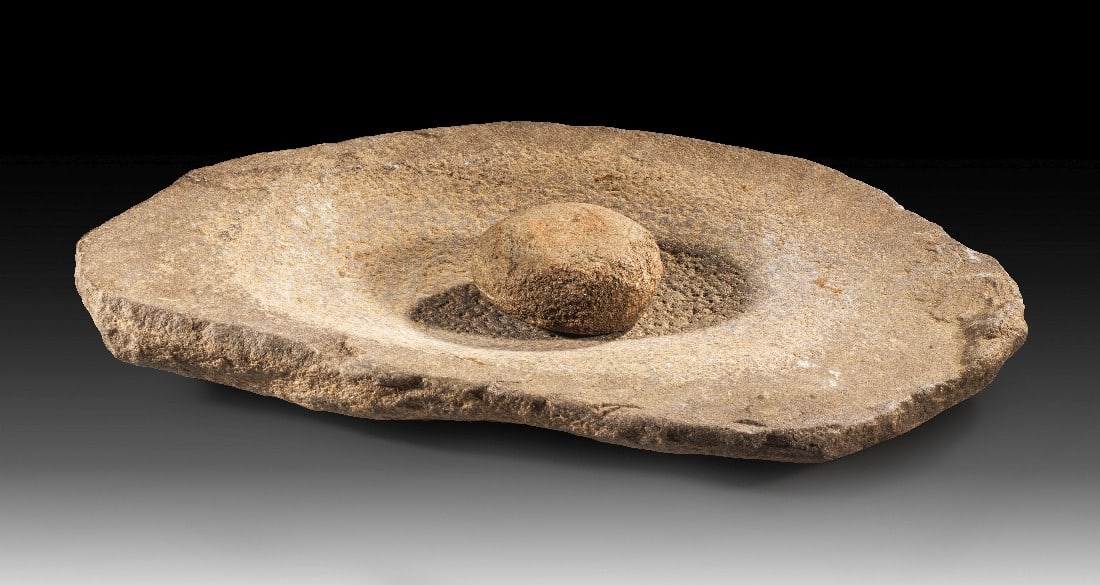 Neolithische Reibschale mit Läuferstein.: Neolithische Reibschale mit Läuferstein. Zentralsahara, 8. - 6. Jt. v. Chr. 45,2 x 31cm, ø Läuferstein 9,5cm. Spitzovale Reibschale aus graubraunem Stein mit tiefer Mulde sowie ein fast runder