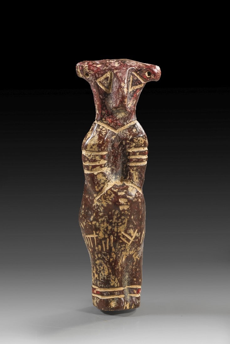 Vinca-Idol.: Vinca-Idol. Südosteuropa, 5. - 4. Jt. v. Chr. H 16,5cm. Rotbrauner Ton. Figur mit vor den Körper gelegten Armen und einem breiten Kopf mit dreieckigen Augen und durchstochenen Löchern an den