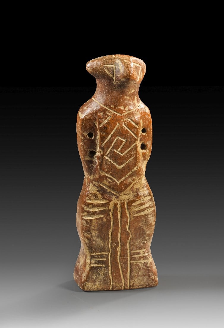 Vinca-Idol.: Vinca-Idol. Südosteuropa, 5. - 4. Jt. v. Chr. H 14cm. Heller, braunroter Ton. Figur mit seitlich angelegten Armen und einem rockartigen Unterleib. Durchstochene Löcher an den Armen und Ohren. Der