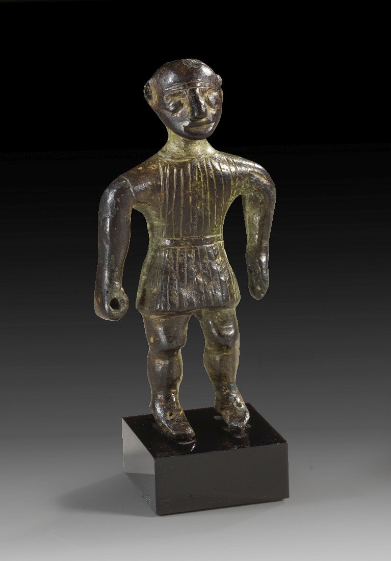 Kelto-iberische Votivstatuette eines Kriegers.: Kelto-iberische Votivstatuette eines Kriegers. 4. - 2. Jh. v. Chr. H 9,5cm und mit Sockel 11,1cm. Vollguss. Kahlköpfiger Mann mit Tunika breitbeinig stehend und die Arme abgewinkelt. Die rechte Hand