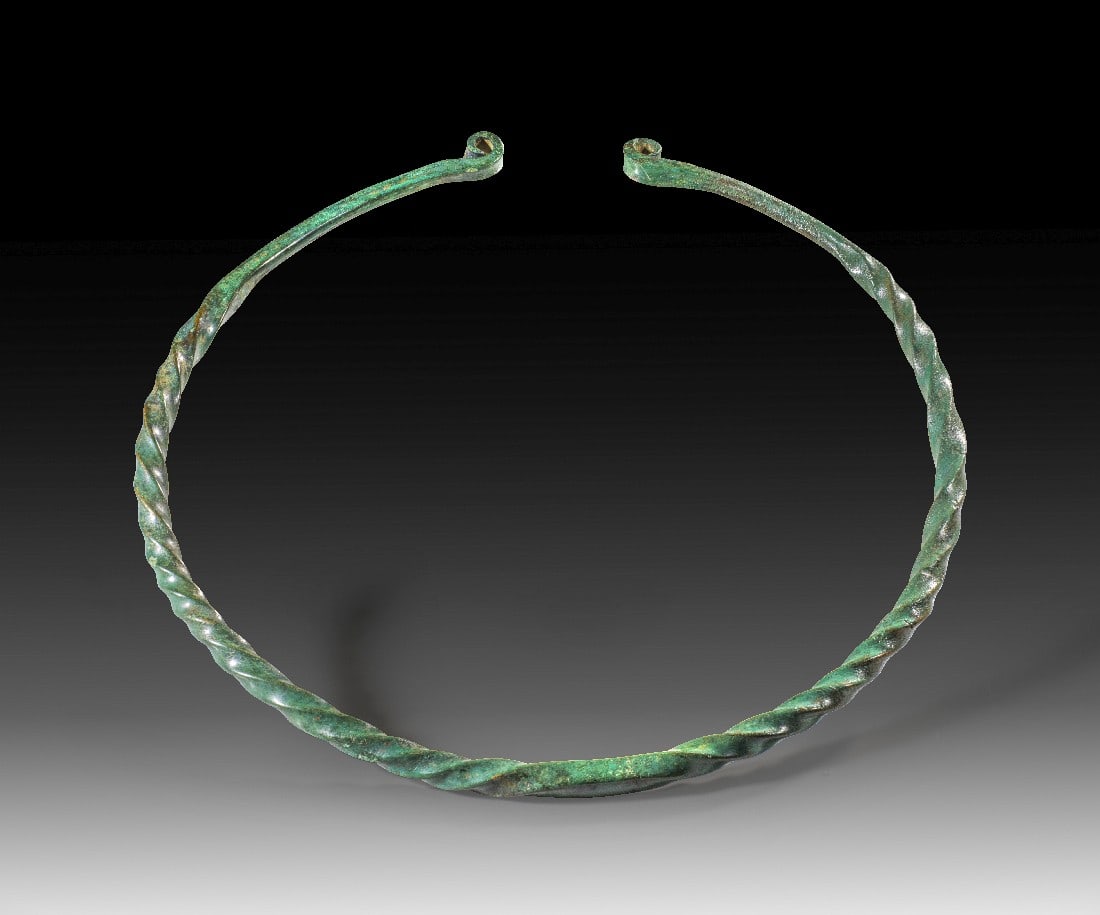 Großer Torques aus Bronze.: Großer Torques aus Bronze. Jüngere Bronzezeit, 8. - 6. Jh. v. Chr. ø 28,8cm, ø des Stabes 1,2cm. Vollguss. Tordierter Reif mit eingerollten Enden. Schöne dunkelgrüne Patina, intakt. Provenienz:
