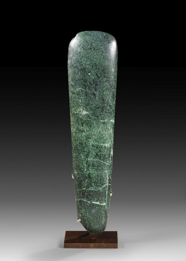 Olmekische Prunkaxt.: Olmekische Prunkaxt. ca. 10. - 4. Jh. v. Chr. Grüner Stein (Jade?), H 32cm, B 8cm. Große, zungenförmige, fein folierte Steinaxt. Kleine Absplitterungen an der Schneide, auf elegantem Ständer.