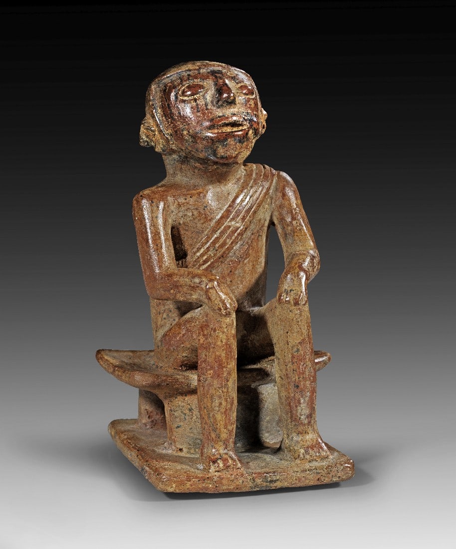 Sitzender Cocakauer.: Sitzender Cocakauer. Carchi, 850 - 1500 n. Chr. H 17,5cm, B der Plinthe 8,5cm. Hohlfigur aus Ton mit rötlich-brauner Engobe und schwarzer Bemalung. Auf einem niedrigen Schemel sitzender Mann, die