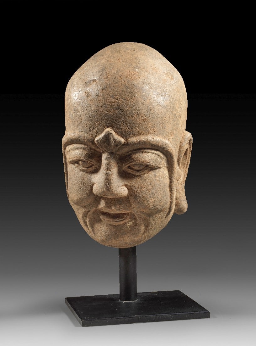 Steinerner Kopf eines Luohan.: Steinerner Kopf eines Luohan. China, Ming-Dynastie, 1368-1644. H ca. 28cm, H ca. 38cm (mit Ständer). Feinkörniger Sandstein, modern gesockelt. Vollplastischer, kraftvoll modellierter Kopf eines