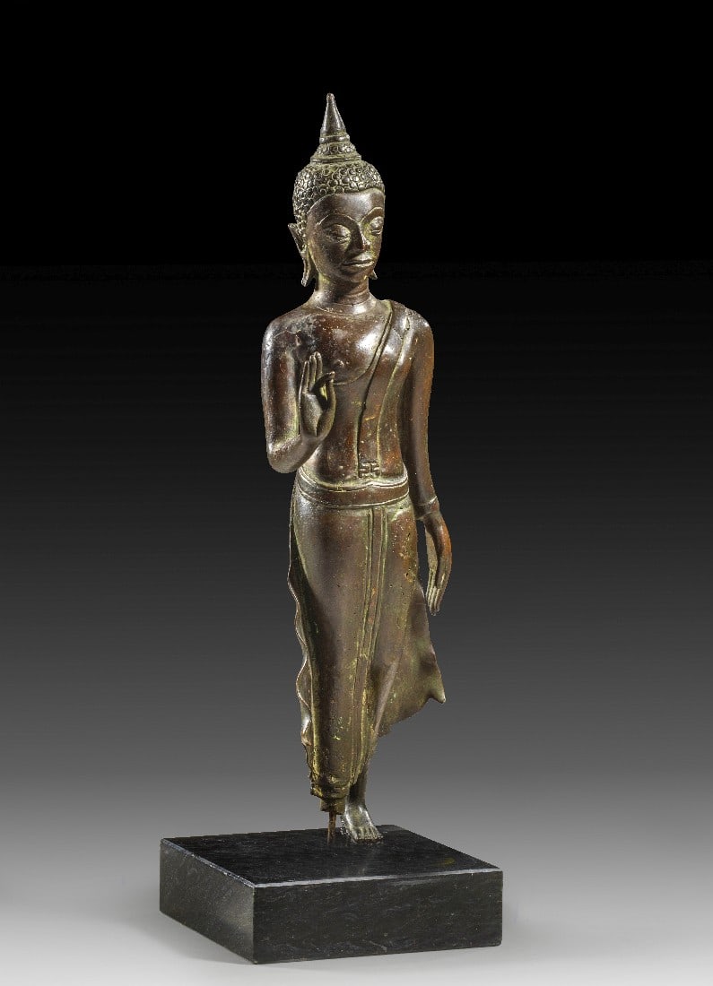 Bronzestatuette eines schreitenden Buddha (Phra Leela).: Bronzestatuette eines schreitenden Buddha (Phra Leela). Südostasien, Sukhotai-Periode, 15. Jh. H 29cm und mit Ständer 32cm. Bronze im verlorenen Wachsverfahren (cire perdue) gegossen, fein