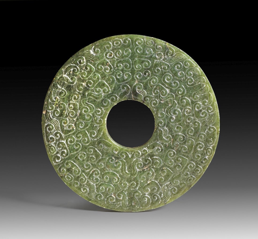 Fein ornamentierte Bi-Scheibe aus Jade.: Fein ornamentierte Bi-Scheibe aus Jade. China, wohl 19. Jh. ø 11,5cm. Dunkelgrün bis schwarz schimmernder Nephrit (Jade), beidseitig dicht mit spiralisierten Yunwen-Mustern graviert. Flache Scheibe