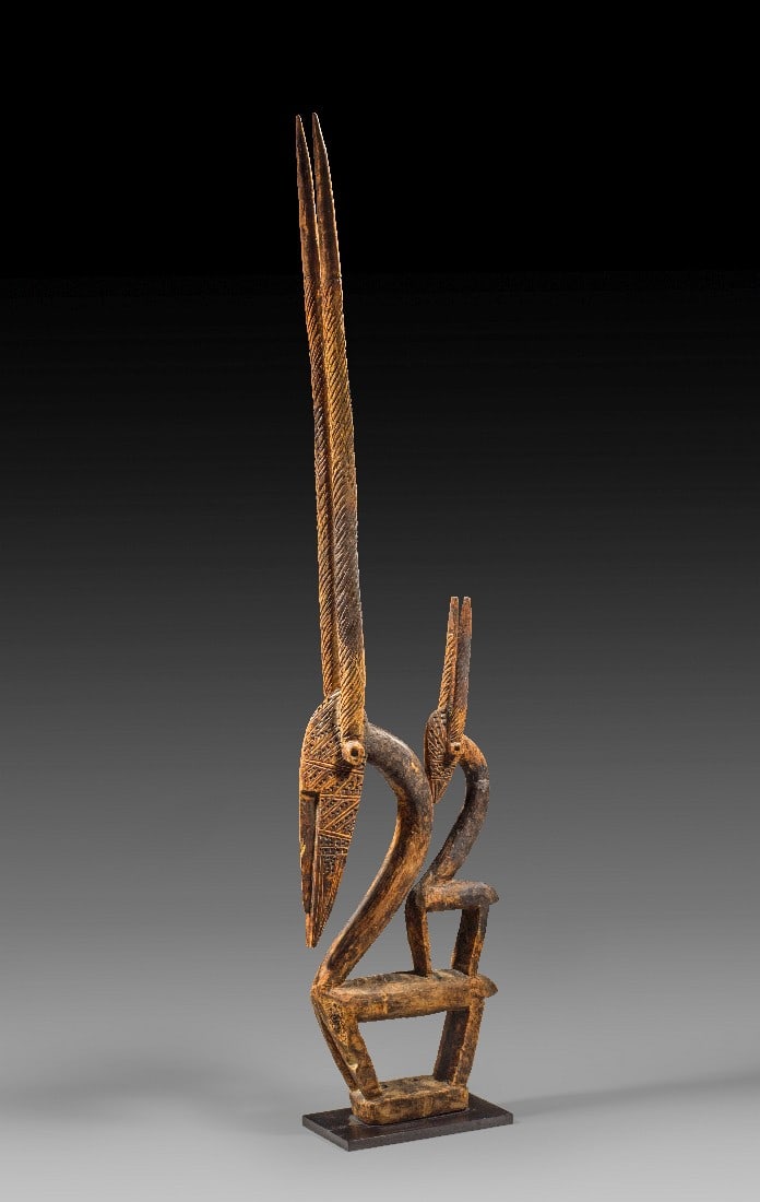 Tanzaufsatz Tschiwara.: Tanzaufsatz Tschiwara. Mali, Bambara, 1. Drittel 20. Jh. H 92,5cm (mit Sockel). Holz. Diese 'Tschiwara' zeigt eine weibliche Antilope mit ihrem Kitz auf dem Rücken. Ihre streng stilisierten Körper