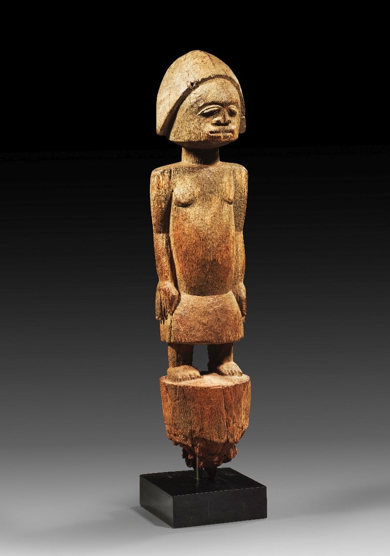 Fon-Fetisch.: Fon-Fetisch. Togo, 1. Viertel 20. Jh. H 67cm, mit Sockel 89cm. Holz. Bekleidete, stehende Figur mit angelegten Armen. Pfostenbekrönung. Witterungspatina, am unteren Ende Termitenfrass. Provenienz: