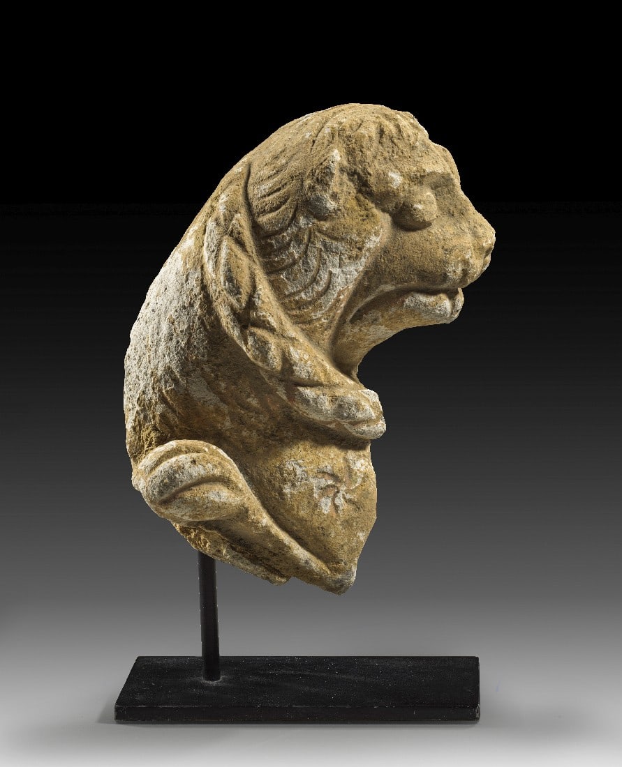 Spätromanischer Löwe.: Spätromanischer Löwe. 12. - 13. Jh. n. Chr. H 17,4cm und mit Ständer 21,3cm. Kalkstein. Kopf, Hals sowie Schwanz eines wahrscheinlich hockenden Löwen, der auf eine Schlange tritt, von der sich