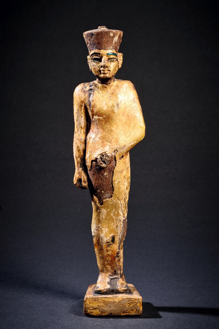 Min-Amun.: Min-Amun. Neues Reich, 1570 - 1069 v. Chr. H 18,5cm. Holz, vergoldet, linkes Auge und rechtes Bartband mit originalen Glaseinlagen. Der schlanke Fruchtbarkeitsgott steht auf einer quaderfoermigen Plin