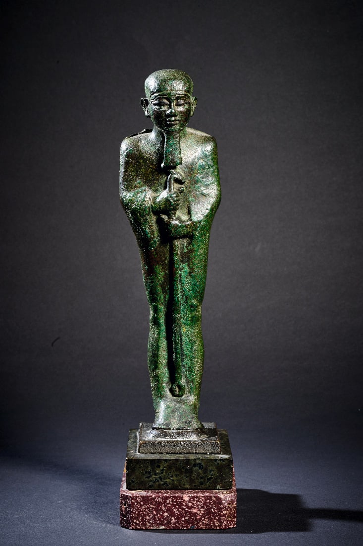 Ptah.: Ptah. Spaetzeit, 26. Dynastie, 664 - 525 v. Chr. H ca. 24,5cm (ohne Sockel). Bronzevollguss. Stehender Ptah in langem Gewand mit Kappe und Goetterbart haelt das Was-Zepter in den Haenden. Auf den Schu