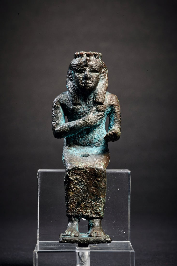 Bronzestatuette der Isis.: Bronzestatuette der Isis. 3. Zwischenzeit bis Spaetzeit, ca. 1070 - 332 v. Chr. H 9cm (mit Einsatzzapfen). Vollguss. In langem Gewand sitzende Isis mit dreigeteilter Peruecke, die Rechte an die Brust 