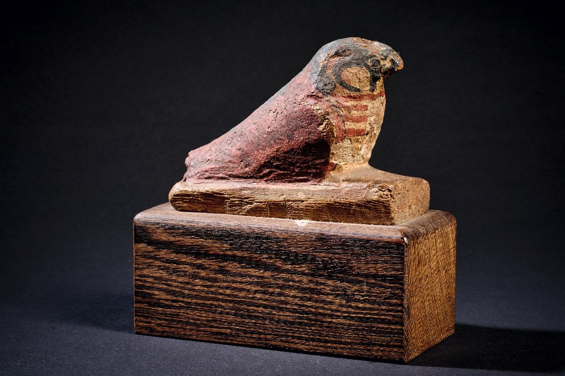 Horusfalke aus bemaltem Holz.: Horusfalke aus bemaltem Holz. Neues Reich, 20. Dynastie, 1185 - 1070 v. Chr. H 7,8cm, L 10,8cm. Mit Stuck ueberzogenes Holz und Bemalung in Weiss, Schwarz und Rot. Auf dem Kopf ein kleines Loch fuer