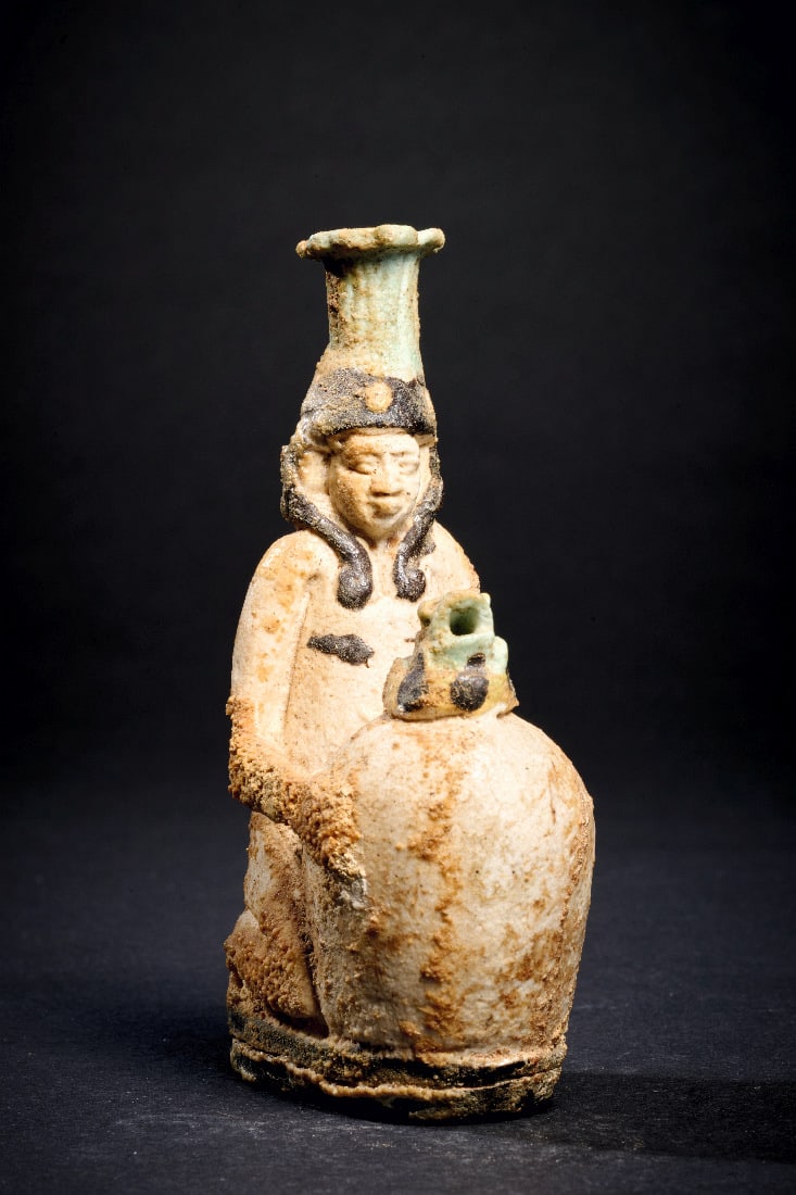 Figuerliche Parfuemflasche.: Figuerliche Parfuemflasche. Spaetzeit, 26. Dynastie, 664 - 525 v. Chr. Fayence, H 9,5cm. Kniende Figur (Hapi?) mit dreigeteilter Peruecke haelt eine grosse eifoermige Vase, auf der ein Frosch sitzt. D