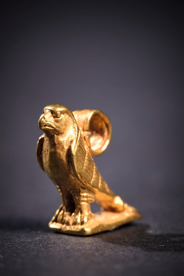 Amulett-Anhaenger mit Horus-Falke aus Gold.: Amulett-Anhaenger mit Horus-Falke aus Gold. Neues Reich, 19. Dynastie, 1295 - 1186 v. Chr. 4,41g, L 1,5cm. Massiver Guss mit Details in Kaltarbeit. Horus-Falke mit Rueckenoese auf einer rechteckigen