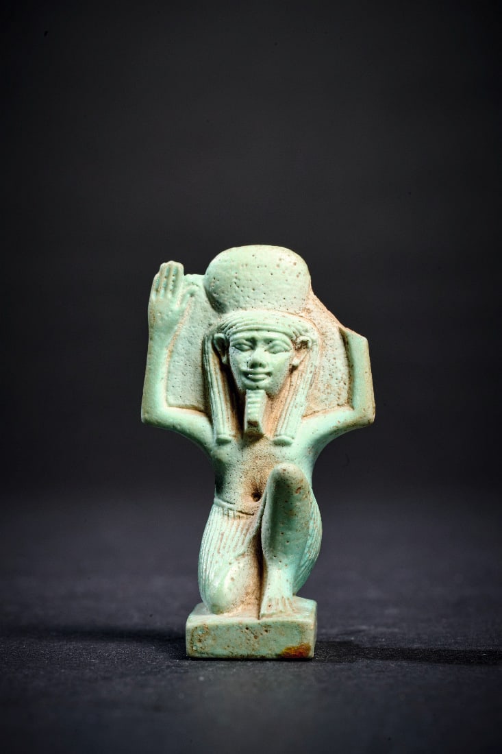 Amulett des Shu.: Amulett des Shu. Spaetzeit, 664 - 322 v. Chr. H 4,2cm. Aus hellgruener Fayence. Kniender Shu mit erhobenen Armen und Sonnenscheibe auf dem Kopf. Auf der Rueckseite oese. Detailreich gearbeitet an der