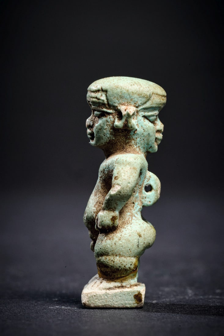 Amulett eines Pataeken.: Amulett eines Pataeken. Spaetzeit, 26. Dynastie, 664 - 525 v. Chr. H 3,7cm. Aus hellgruener Fayence. Mit Januskopf und Rueckenoese, auf einer rechteckeckigen Standplatte. Ein Ohr fehlt. Provenienz: