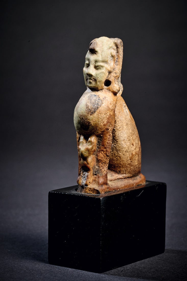 Amulett der Sphinx.: Amulett der Sphinx. Spaetzeit, 1. Jt. v. Chr. H 9,2cm (mit Sockel), H 6,2cm (ohne Sockel). Aus hellgruener Fayence mit schwarzer Bemalung. Hockende Sphinx mit Katze zwischen den Vorderbeinen. Reste