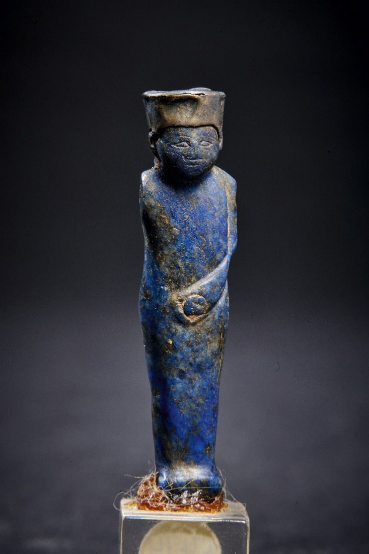 Statuette des Gottes Min.: Statuette des Gottes Min. Spaetzeit, 1. Jt. v. Chr. H 5cm (m. Sockel), H 3,8cm (o. Sockel). Aus Lapislazuli, Krone aus Goldblech. Min ist die altaegyptische Schoepfungsgottheit. Rechter Arm fehlt.
