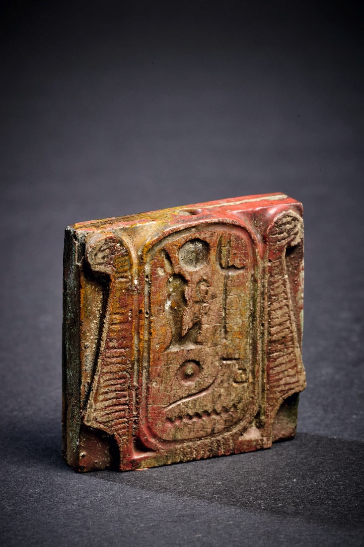 Amulett mit Kartusche und Apisstier.: Amulett mit Kartusche und Apisstier. Neues Reich, 22. Dynastie, 943 - 716 v. Chr. B 3,8cm, H 4cm, T 1cm. Aus glasiertem Steatit. Quadratisches Relief mit Laengsbohrung, auf der einen Seite eine von