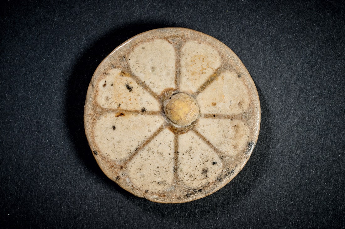 Rosetten-Einlage aus Fayence.: Rosetten-Einlage aus Fayence. Neues Reich, 20. Dynastie, 1196 - 1070 v. Chr. ? 4,2cm. Scheibe mit weisser Rosette mit acht weissen Blaettern und gelber Halbkugel im Zentrum auf hellbraunem Grund.