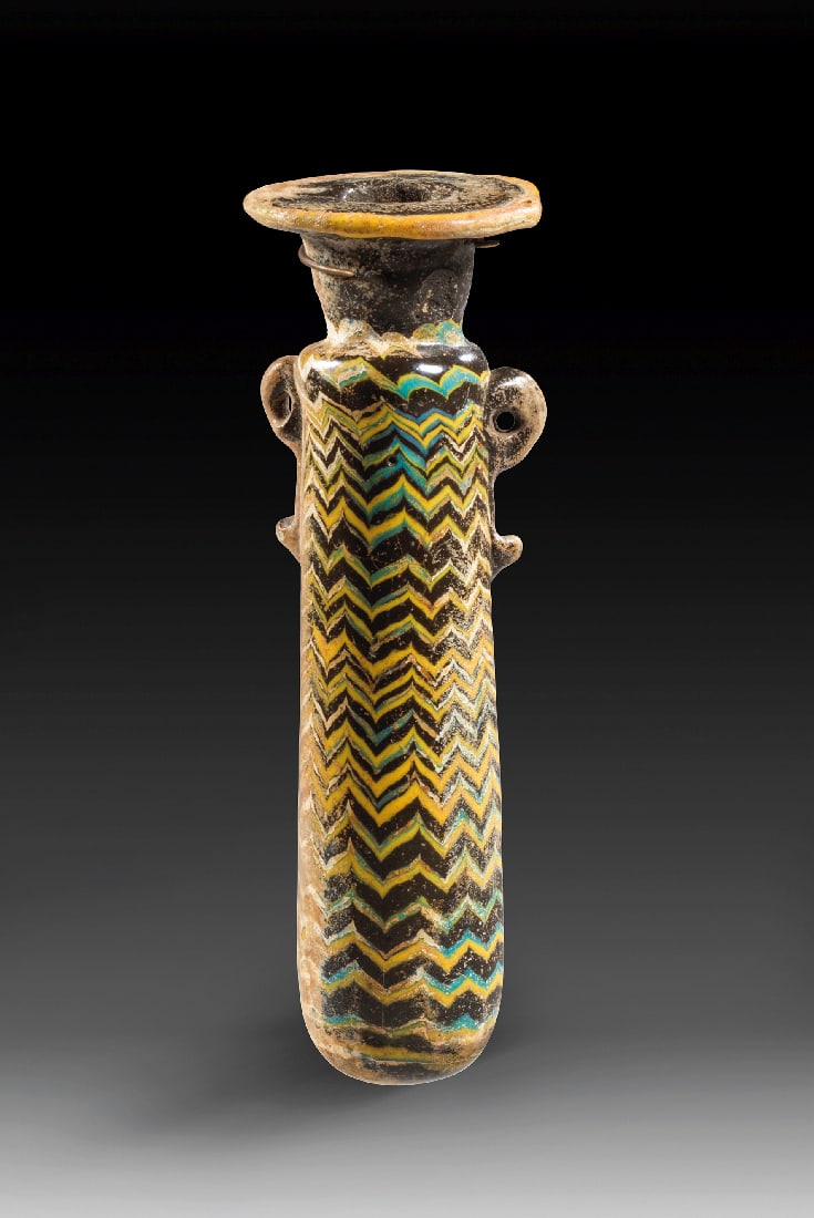 Alabastron mit polychromem Chevrondekor.: Alabastron mit polychromem Chevrondekor. oestliches Mittelmeergebiet, 6. - 4. Jh. v. Chr. H 10,5cm. Opak dunkel (schwarzblaues) Glas. Sandkerntechnik. Schlanker, langgestreckter, nach unten leicht kon