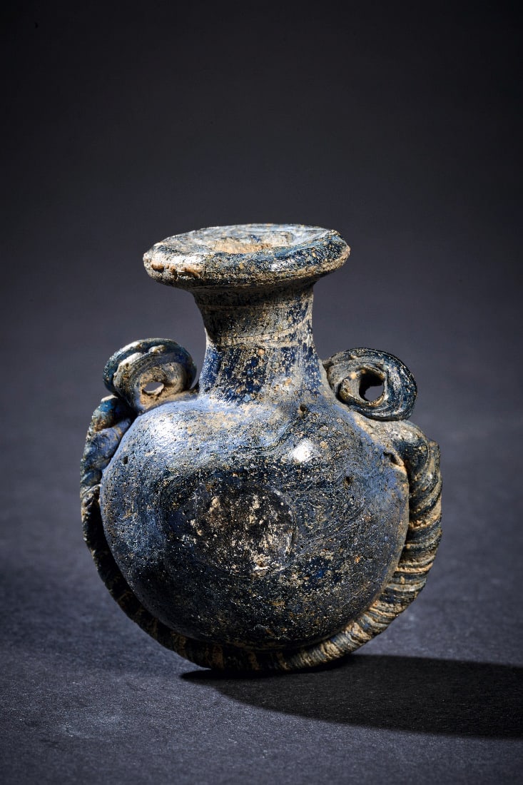 Seltenes linsenfoermiges Glasflaeschchen mit Kordeldekor.: Seltenes linsenfoermiges Glasflaeschchen mit Kordeldekor. oestliches Mittelmeergebiet, 4. - 3. Jh. v. Chr. H 4cm, ? 4cm. Glas von tiefblauer, heute stellenweise dunkel patinierter und irisiert