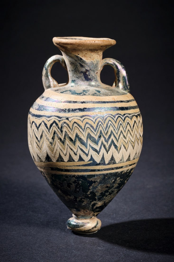Amphoriskos mit kontrastierendem Zickzackdekor.: Amphoriskos mit kontrastierendem Zickzackdekor. oestliches Mittelmeergebiet, wohl 5. Jh. v. Chr. H 8,5cm. Glas von blaeulicher Grundfarbe, stellenweise irisierend und mit partieller Verwitterung.