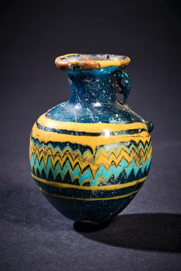 Aryballos mit polychromem Zickzackdekor.: Aryballos mit polychromem Zickzackdekor. oestlicher Mittelmeerraum, 5. - 4. Jh. v. Chr. H 6cm. Glas, opak dunkelblau. Sandkerntechnik. Kugeliger Gefaesskoerper mit leicht eingezogenem Hals und