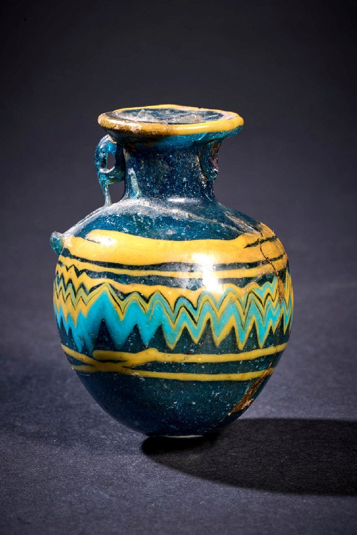 Polychrom verzierter Kugelaryballos aus blauem Glas.: Polychrom verzierter Kugelaryballos aus blauem Glas. oestlicher Mittelmeerraum, 6. - 5. Jh. v. Chr. H 5,5cm, ? 4cm. Transluzides, tiefblaues Glas. Sandkerntechnik. Glasgefaess von gedrungener, nahezu