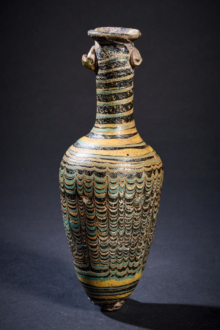 Grosser Amphoriskos mit Girlandendekor in Gelb und Tuerkis.: Grosser Amphoriskos mit Girlandendekor in Gelb und Tuerkis. Mittelmeerraum, 1. Jh. v. - 1. Jh. n. Chr. H 15,1cm. Glas, dickwandig, in opakem Schwarz. Sandkerntechnik. Schlanker, hochgezogener Gefaessk