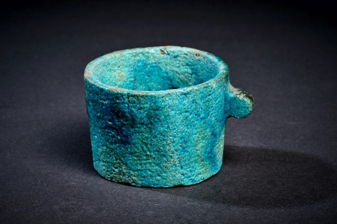 Tasse aus Fayence.: Tasse aus Fayence. Neues Reich, 18. Dynastie, 1550 - 1292 v. Chr. H 4,4cm, ? 5,8cm. Tuerkise Fayence. Zylindrische Tasse mit flachem Boden und einem seitlichen Noppenhenkel. Intakt. Provenienz: