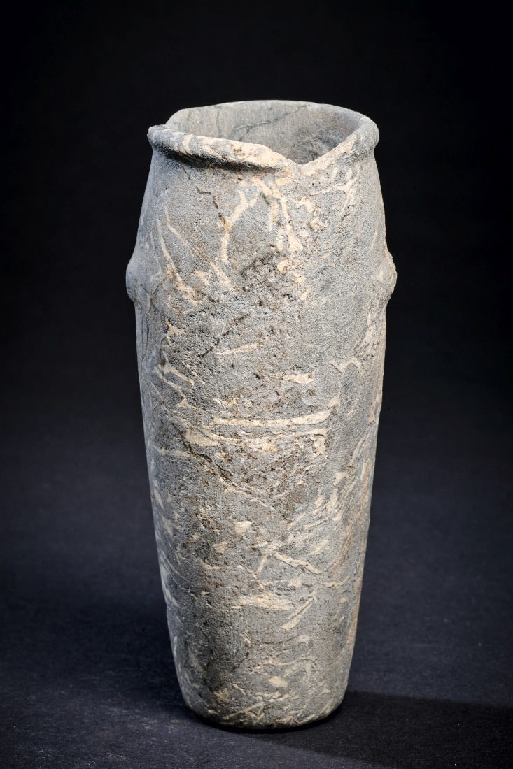 Schlankes Gefaess mit Schnuroesen aus Magmatite.: Schlankes Gefaess mit Schnuroesen aus Magmatite. Prae- bis fruehdynastisch, 3200 - 2740 v. Chr. H 12,1cm, ? 4,8cm. Grauer Hartstein mit weissen Einschluessen. Hohes, leicht konvexes Gefaess mit