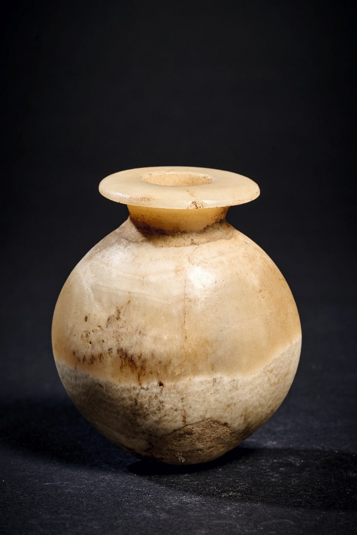 Interessantes herzfoermiges Salbgefaess aus Alabaster.: Interessantes herzfoermiges Salbgefaess aus Alabaster. Neues Reich, 1550 - 1070 v. Chr. oder spaeter. H 6,9cm, B 5,9cm. Zweilagiger Alabaster. Runder, im Querschnitt spitzovaler Koerper mit Tellermuen