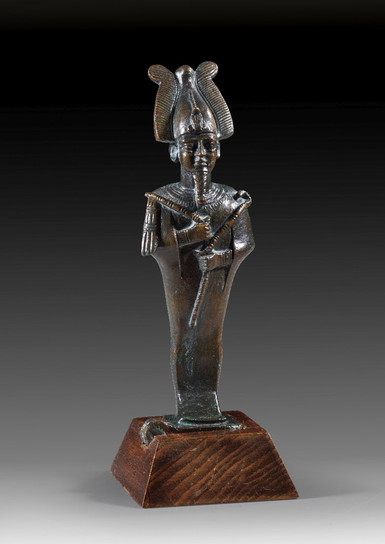 Bronzestatuette des Osiris.: Bronzestatuette des Osiris. 3. Zwischenzeit bis Spaetzeit, ca. 1070 - 664 v. Chr. H 13cm, mit Holzsockel 15cm. Bronzevollguss. Mumiengestaltige Figur des Gottes Osiris mit Atef-Krone und Uraeus.