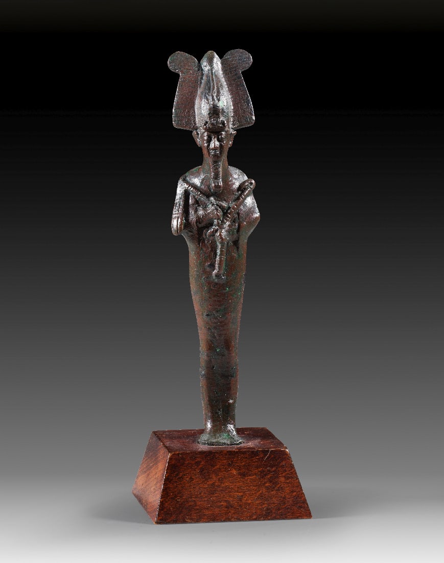 Bronzestatuette des Osiris.: Bronzestatuette des Osiris. 3. Zwischenzeit bis Spaetzeit, ca. 1070 - 664 v. Chr. H 14,5cm, mit Holzsockel 17,5cm. Bronzevollguss. Mumiengestaltige Figur des Gottes Osiris mit Atef-Krone und Uraeus.