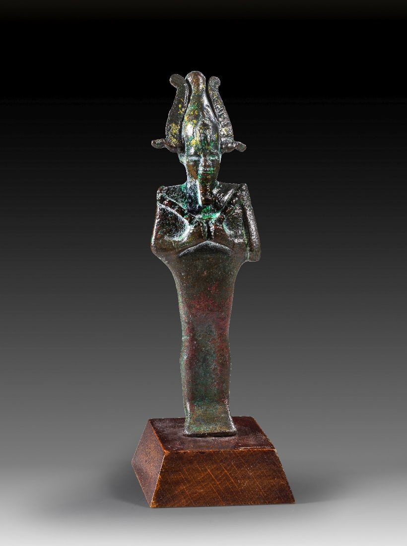 Bronzestatuette des Osiris.: Bronzestatuette des Osiris. 3. Zwischenzeit bis Spaetzeit, ca. 1070 - 664 v. Chr. H 13,2cm (ohne Sockel), mit Holzsockel 15cm. Bronzevollguss. Mumiengestaltige Figur des Gottes Osiris mit Atef-Krone