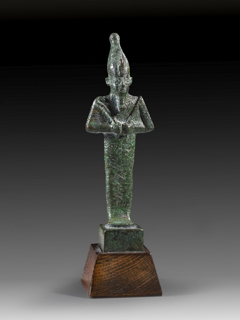 Bronzestatuette des Osiris.: Bronzestatuette des Osiris. 3. Zwischenzeit bis Spaetzeit, ca. 1070 - 664 v. Chr. H 15,5cm (mit Bronzesockel), mit Holzsockel 19cm. Bronzevollguss. Mumiengestaltige Figur des Gottes Osiris mit
