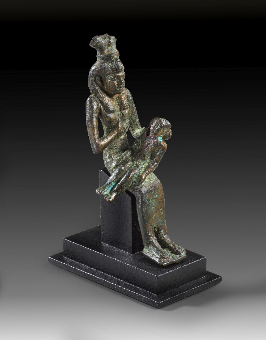Bronzestatuette der Isis mit Horusknaben, sog. Isis Lactans.: Bronzestatuette der Isis mit Horusknaben, sog. Isis Lactans. Spaetzeit, 26. Dynastie, 664 - 525 v. Chr. H 10,3cm und mit Sockel 11,7cm. Vollguss. Sitzende Isis mit Resten einer Hathorkrone gibt dem