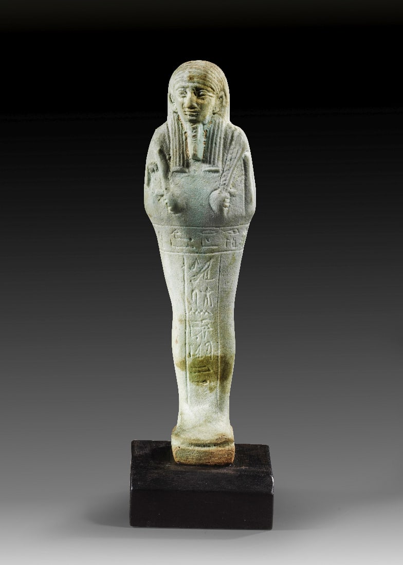 Ushebti des Hor.: Ushebti des Hor. Spaetzeit, 30. Dynastie, ca. 380 - 342 v. Chr. H 18,8cm (mit Sockel), H Sockel 1,8cm. Hellgruene Fayence. Mumienfoermig mit Rueckenpfeiler, Peruecke, Bart sowie Hacke, Saattaeschchen 