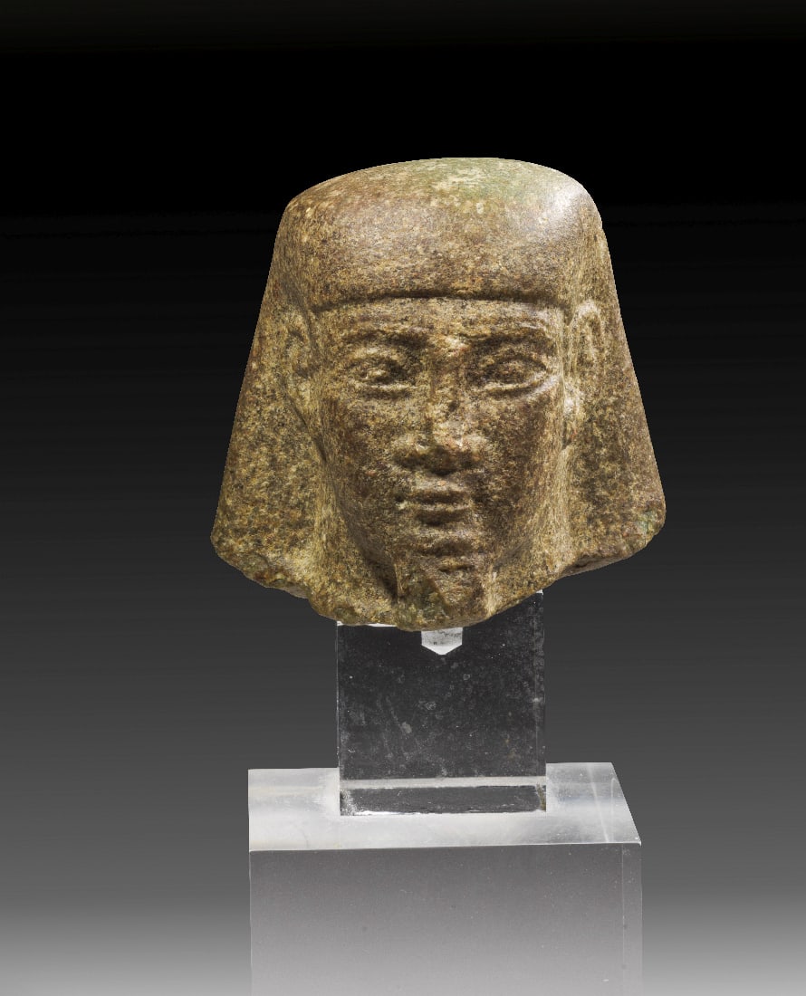 Miniaturkopf eines Wuerfelhockers .: Miniaturkopf eines "Wuerfelhockers". Spaetzeit, 26. - 31. Dynastie, 664 - 332 v. Chr. H 6,5cm (ohne Sockel), 18cm (mit Sockel). Gruener Basalt. Mit Khat-Peruecke und Resten des Zeremonialbartes unter 