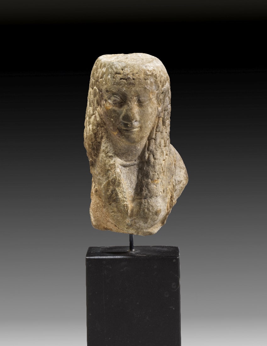 Bueste der Isis.: Bueste der Isis. Ptolemaeisch, 3. - 1. Jh. v. Chr. H 5,5cm. Kalkstein. Teil einer Figur mit Resten des Oberkoerpers mit entbloesster Brust und dem Kopf, der eine dreigeteilte Peruecke traegt.