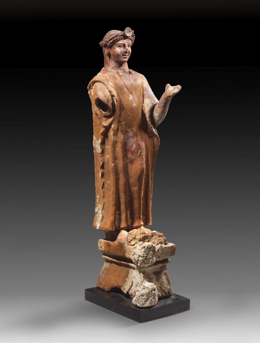 Adorant mit Lorbeerkranz.: Adorant mit Lorbeerkranz. Phoenizien, ca. Mitte 5. Jh. v. Chr. Rotbraune Terrakotta, H 67cm. Ein stehender junger Mann gekleidet in ein knoechellanges Gewand mit engem Halsausschnitt. Der linke Fuss