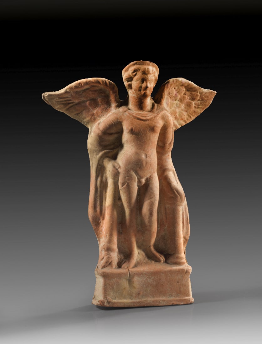 Statuette eines Genius.: Statuette eines Genius. Roemisch, 1. - 3. Jh. n. Chr. H 20cm, B 15cm. Aus rotbrauner Terrakotta, matrizengeformt, rueckwaertig ein Brennloch. Auf einer Basis stehender, nackter Juengling mit Fluegeln
