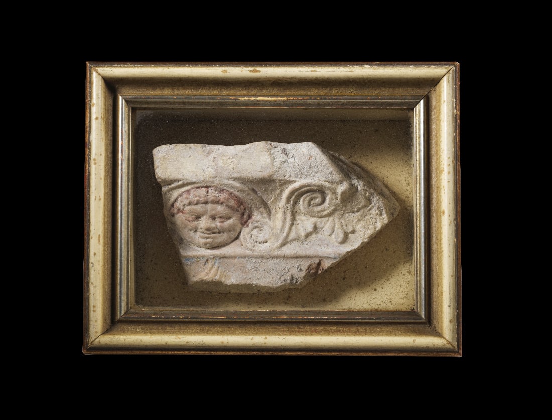Etruskisches Architekturfragment mit figuerlichem Fries.: Etruskisches Architekturfragment mit figuerlichem Fries. 4. - 3. Jh. v. Chr. H 9,7cm, B 18,3cm, Kasten 20,8 x 26,4 x 9,6cm. Teil von einem Gesims oder Architrav aus hellbrauner Terrakotta, darueber
