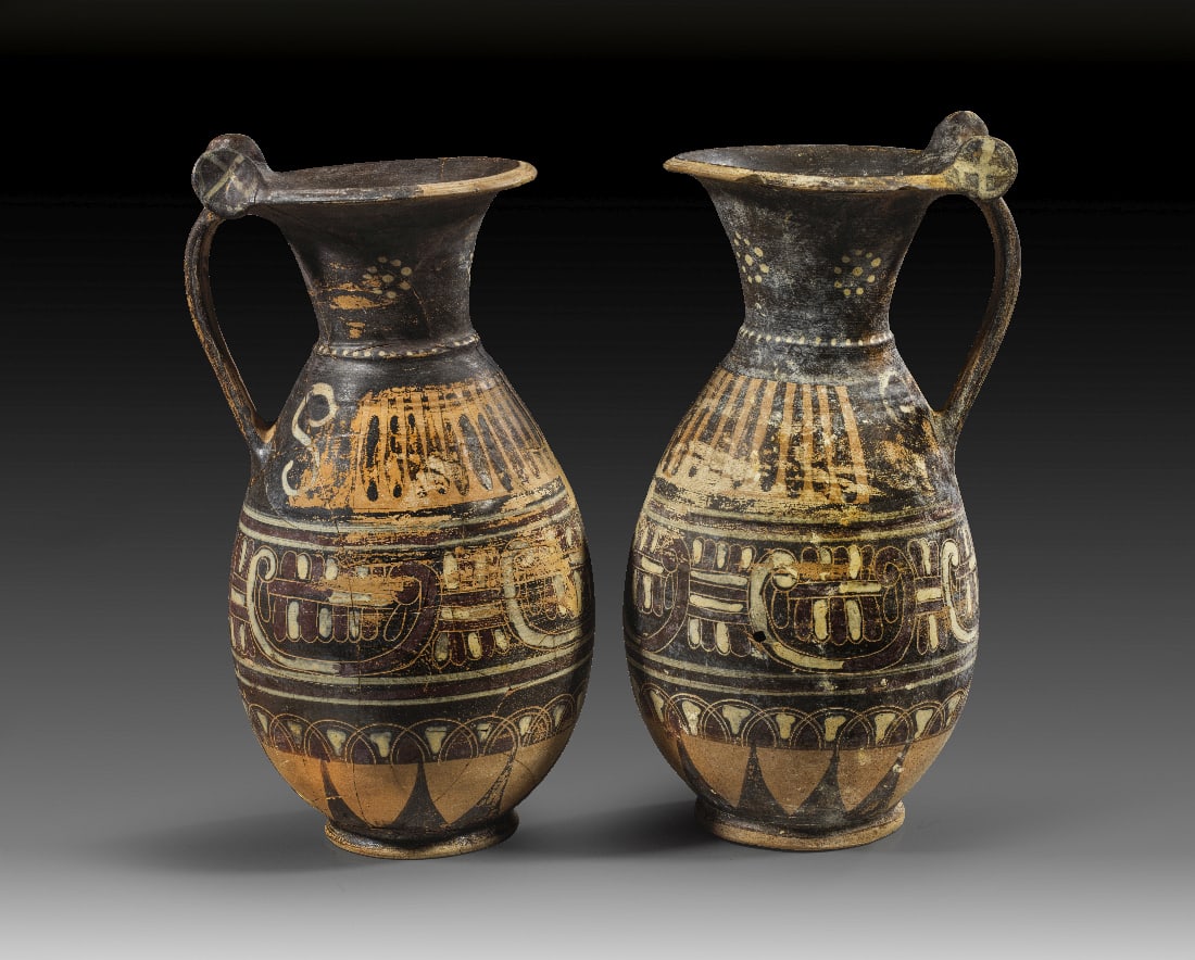 Paar italo-korinthische schwarzfigurige Olpen aus der Gruppe der phoenikischen Palmetten.: Paar italo-korinthische schwarzfigurige Olpen aus der Gruppe der phoenikischen Palmetten. 580 - 560 v. Chr. H 30,4 und 30,6cm, ? 16,3 und 15,1cm. Weinkannen mit flacher Muendung und seitlichen