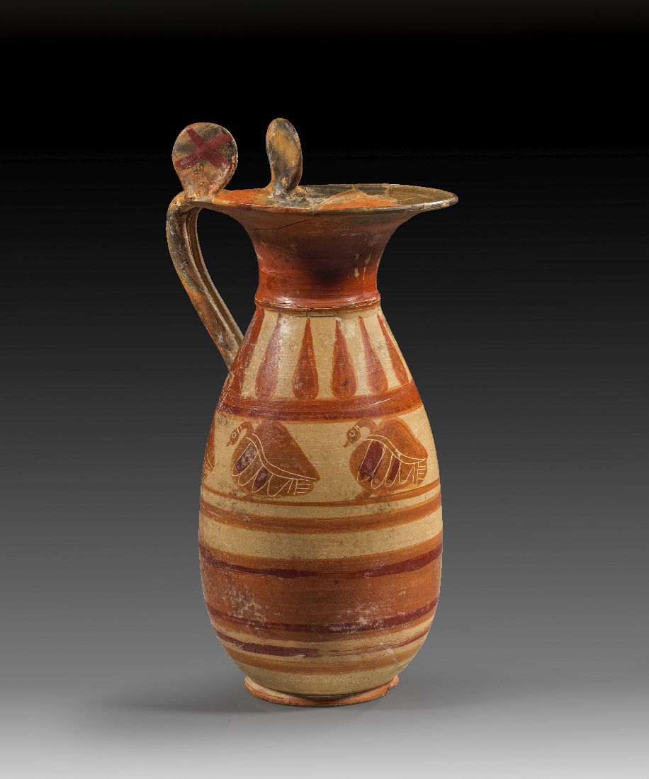 Italo-korinthische schwarzfigurige Olpe.: Italo-korinthische schwarzfigurige Olpe. 570 - 560 v. Chr. H 30,6cm, ? Muendung 14cm. Weinkanne mit Trichtermuendung und grossen Rotellen am Henkelansatz. Auf dem Koerper zwischen in Rot gemalten Lini